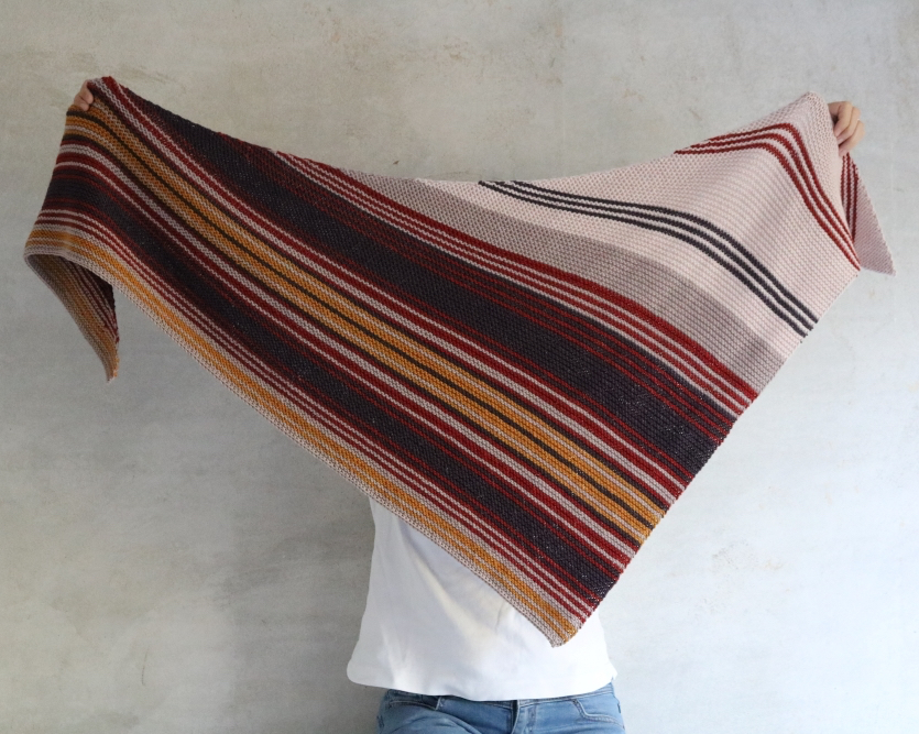 A knitted striped shawl in warm colours